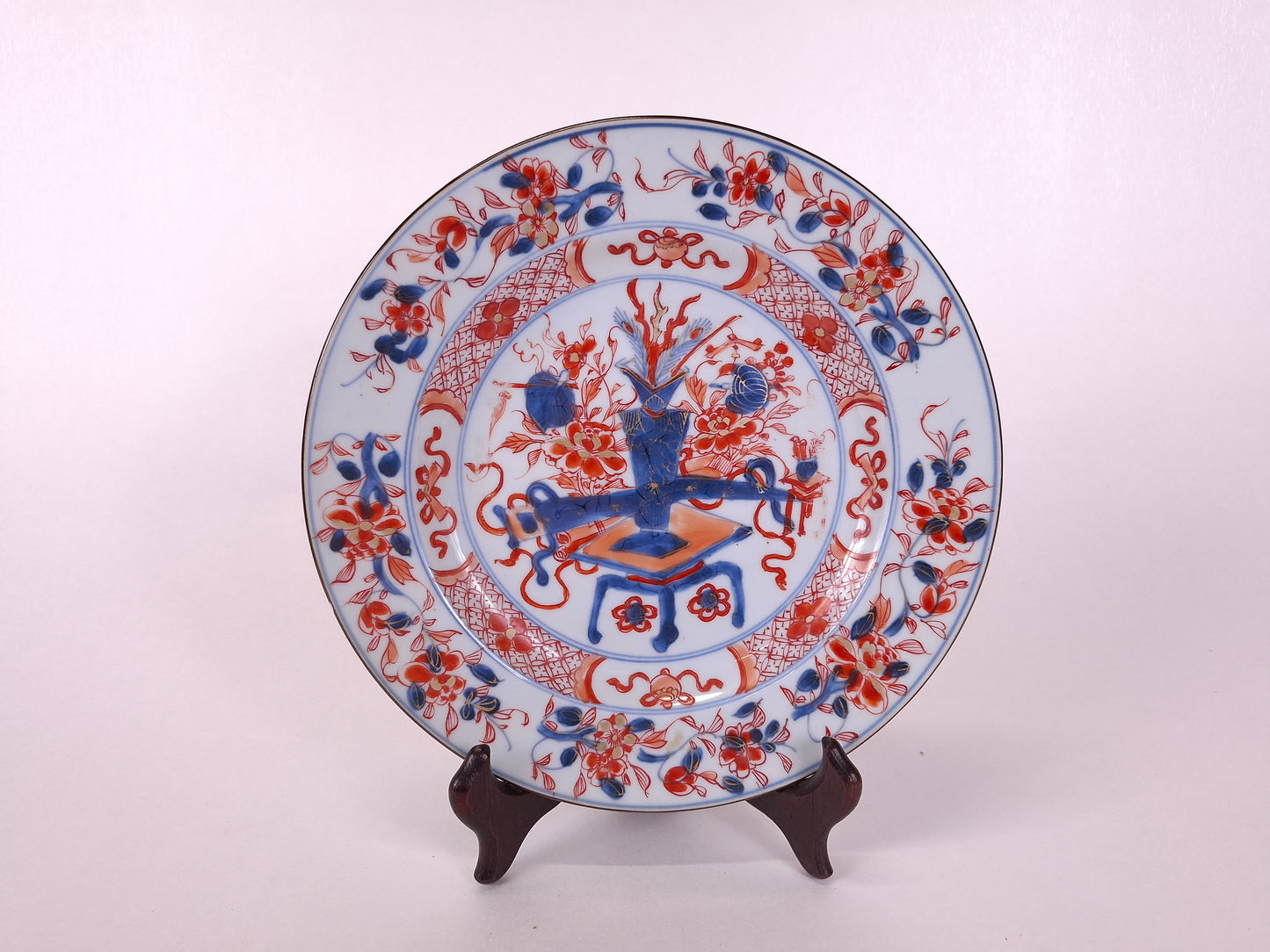 Decorative ceramic plate with intricate red and blue patterns on a white background