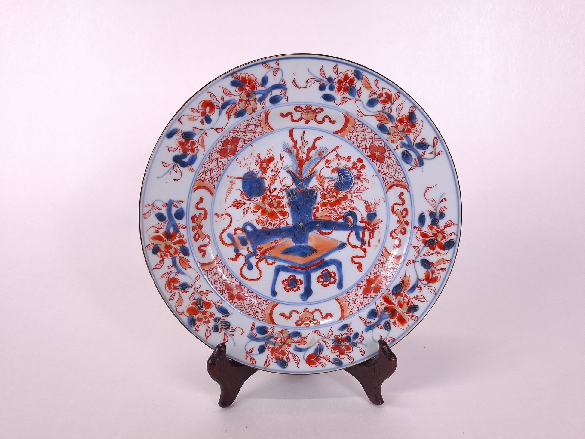 Decorative ceramic plate with intricate red and blue patterns on a white background