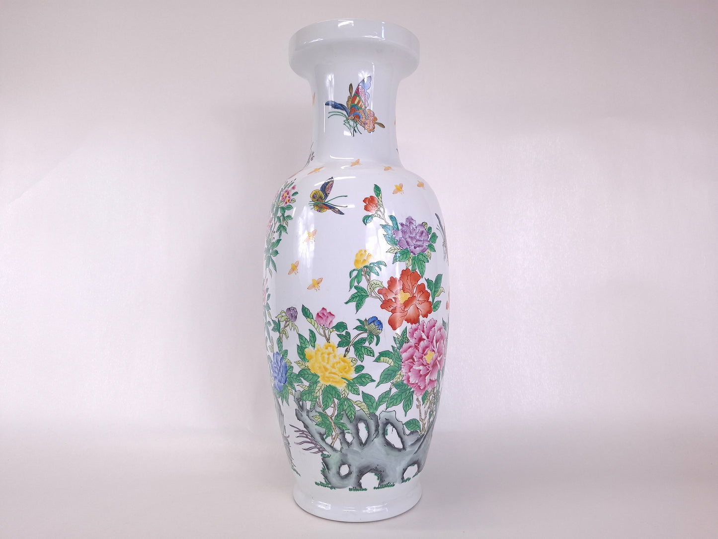 A white ceramic Chinese Qianlong style vase decorated with a colorful hand-painted floral and butterfly pattern, set against a plain light background.